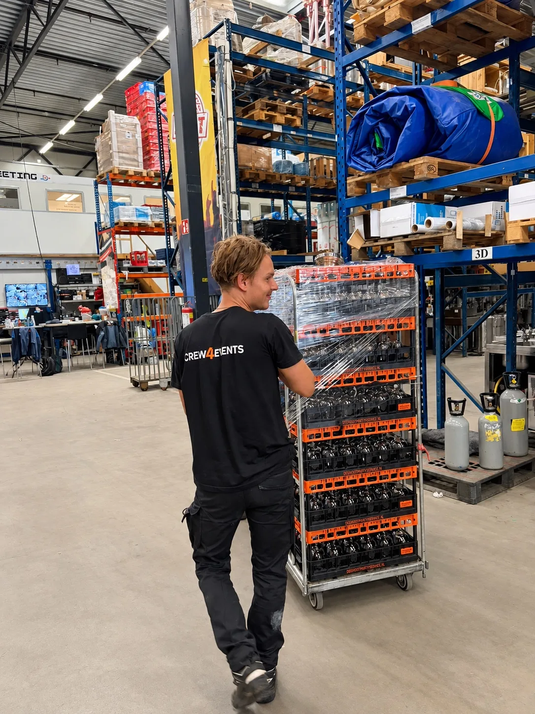 Een Crew4Events-medewerker rijdt een kar met eventmateriaal door het magazijn